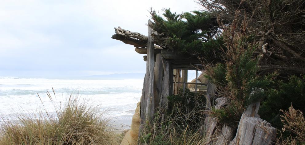 Perched on the edge of the cliff-face at Gemstone Beach in Southland is the shell of a house....