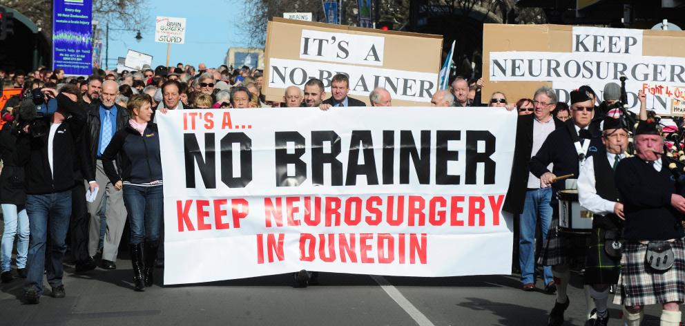 Marchers hold up a signs during a protest to keep neurosurgery services in Dunedin. Photo: ODT files