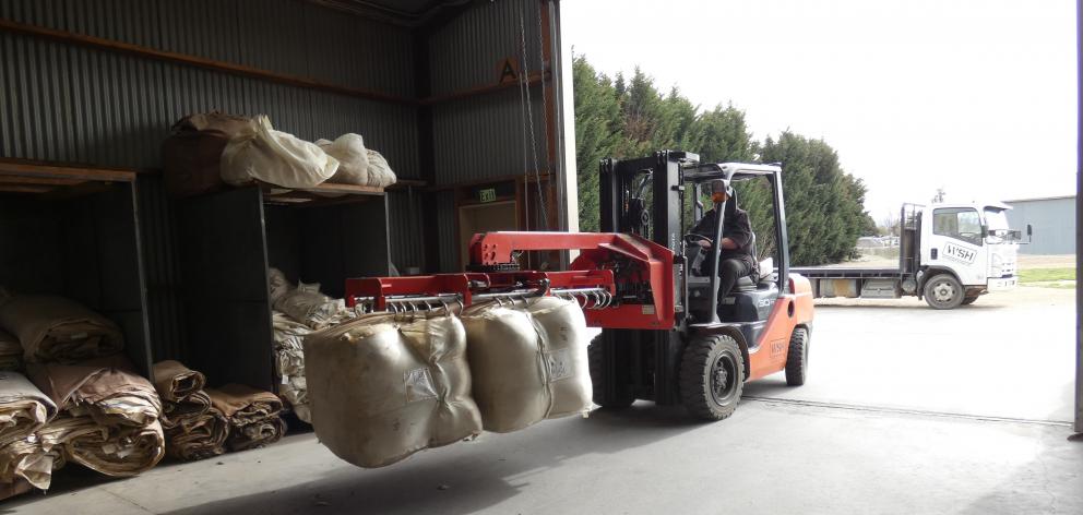WS Hickey & Son Ltd wool handler Al Naylor shifts wool bales during a busy work day. Photo: Adam Burns
