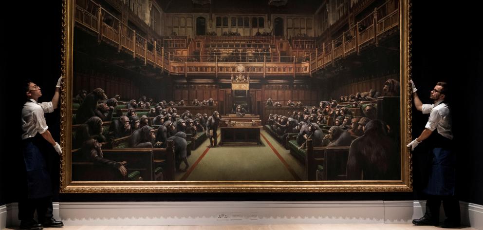 Sotheby's staff pose for a photograph with Banksy's 'Devolved Parliament'. Photo: Reuters