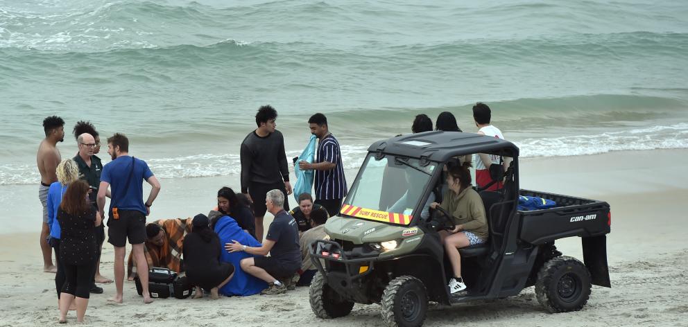 Off-duty surf life-savers, St John paramedics and water rescue squad members comfort four people...
