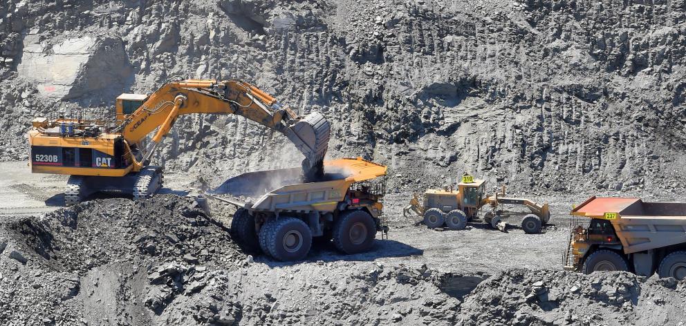 A road grader is dwarfed by an excavator and dump trucks extracting rock in the Coronation pit....