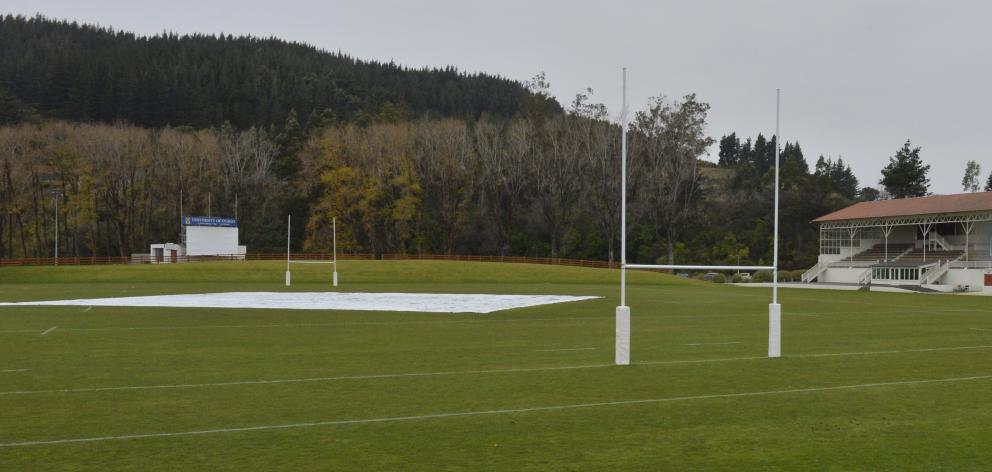 The pitch block at the University Oval was under cover yesterday. Wet weather has left the area sodden and heavy underfoot. Photo: Gerard O'Brien