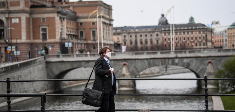 A man wearing a protective mask walks past the Royal Swedish Opera, amid the Covid-19 outbreak in Stockholm. Photo: Reuters