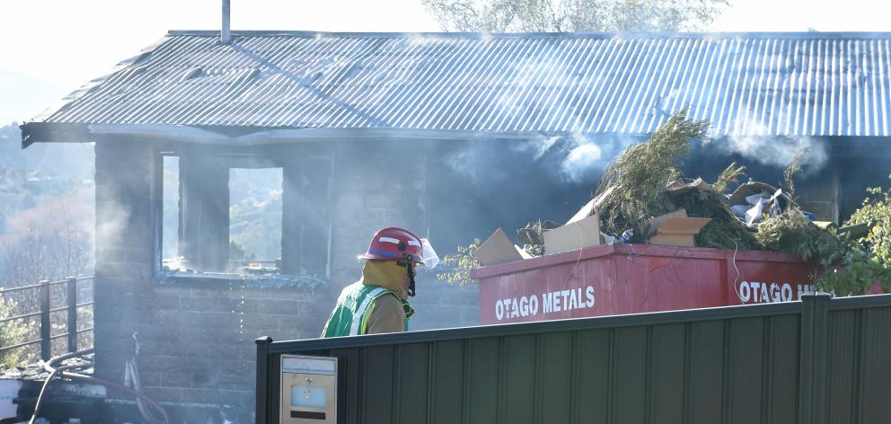 A firefighter stands in front of the smoking remains of the house. Photo: Peter McIntosh