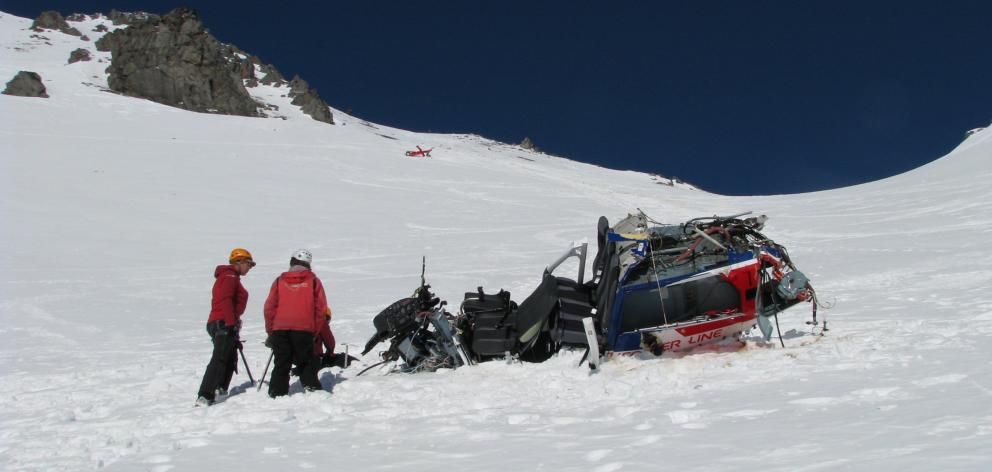 Investigators examine the main fuselage of the helicopter, with the tail section about 300m...