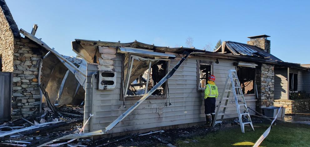 A Fenz firefighter checks on the remains of a house, off Tucker Beach Rd, in Queenstown, which...