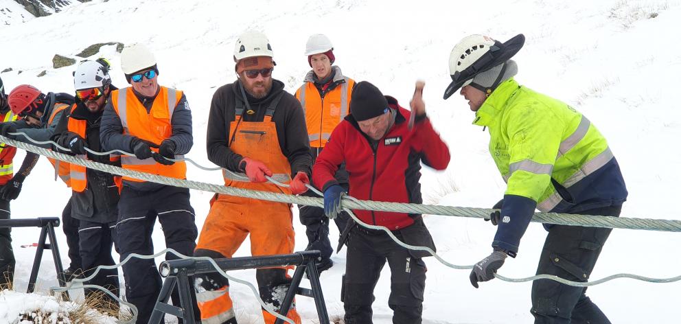 NZSki staff pull the cable taut as specialist metal rope splicer Hannes Koller thrashes the...