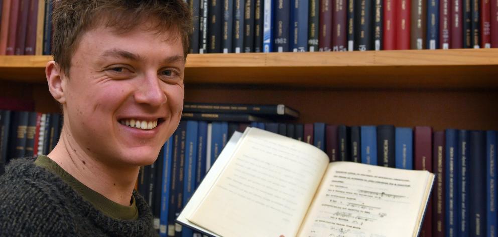 Conor Hassan holds his great-grandfather Miles Barnett’s master’s thesis in the physics archives...