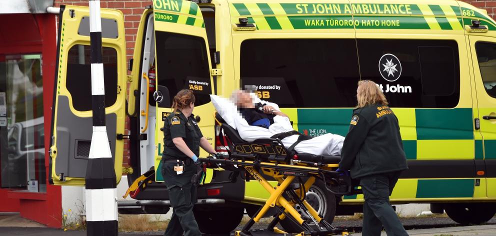 St John staff carry an injured woman into an ambulance in Green Island yesterday. PHOTO: PETER...