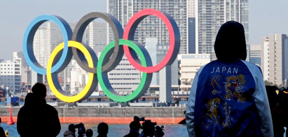 Bystanders watch as giant Olympic rings are reinstalled at Tokyo's Odaiba Marine Park in December...