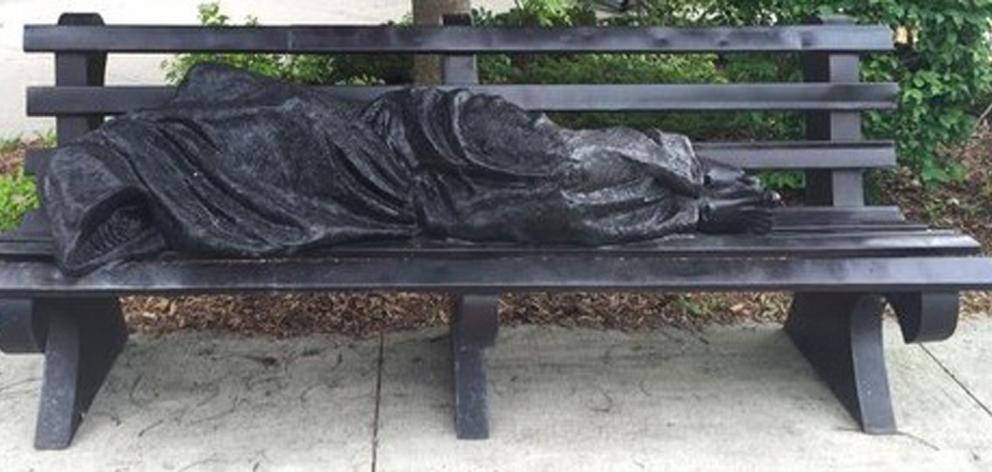 The Homeless Jesus sculpture lies on a bench at the campus of King’s University College at...