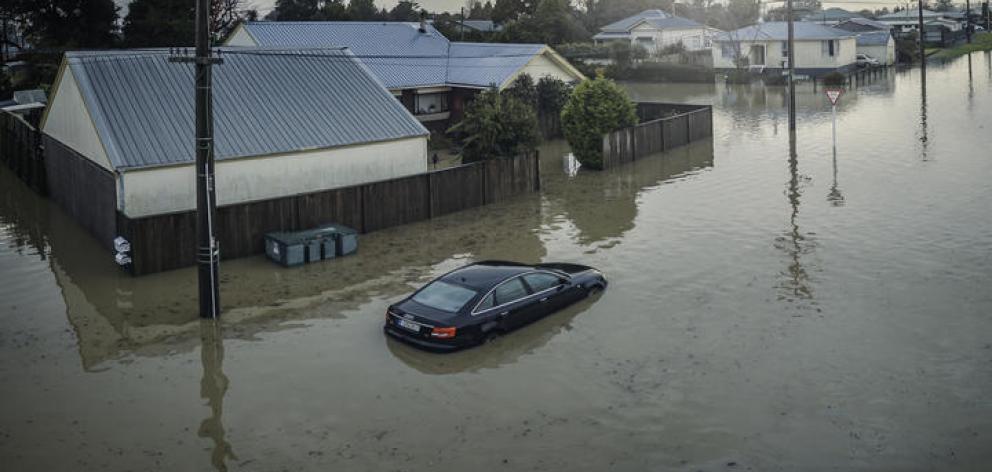 A partly-submerged car outside flooded Westport houses. Photo: Supplied/NZ Defence Force
