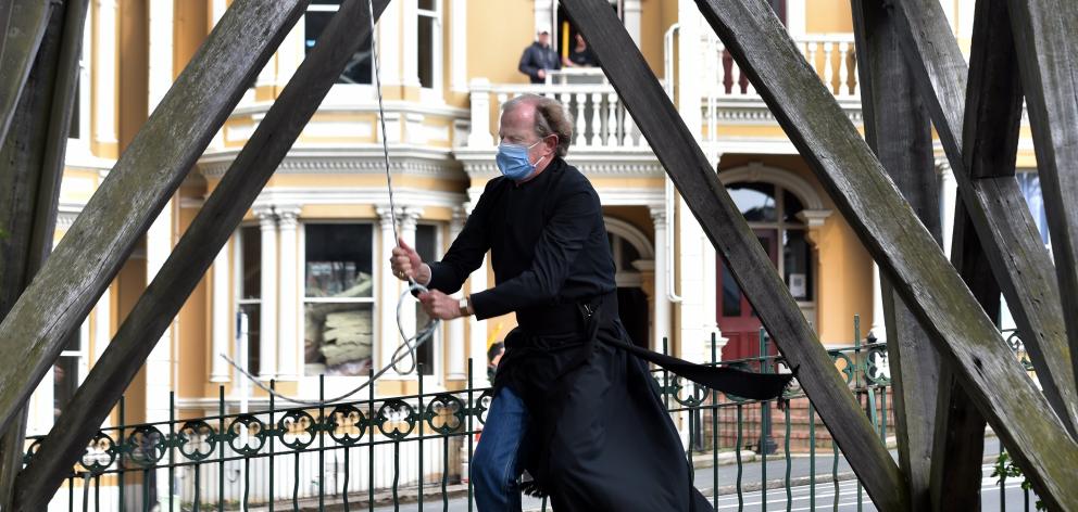  Minister Bruce Aitken rings the bell outside St Paul’s Cathedral, in Dunedin, at 1pm yesterday,...