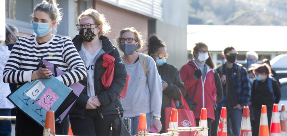 A queue of shoppers with masks in place wait their turn to enter Gardens New World in Dunedin...