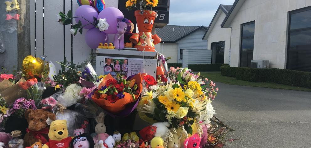 An ever-increasing collection of flowers and toys have been laid on the driveway of the Queen St home where three children were killed last week. PHOTO: HELEN HOLT