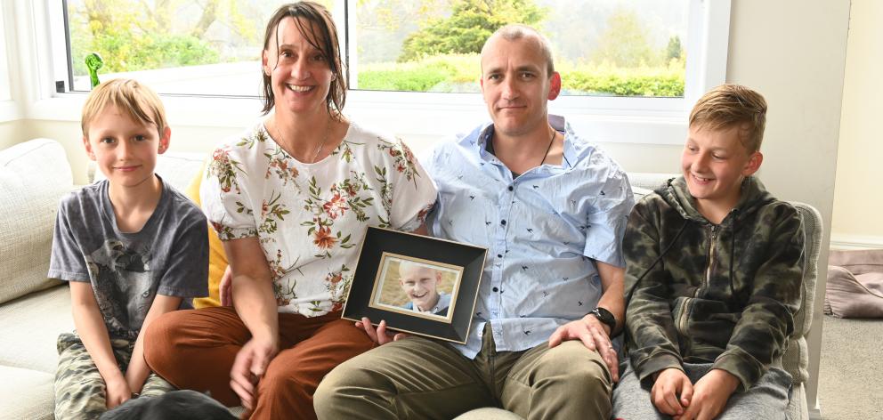 Carolyn and Ben Robins hold a photo of  Toby. With them are their sons 
...