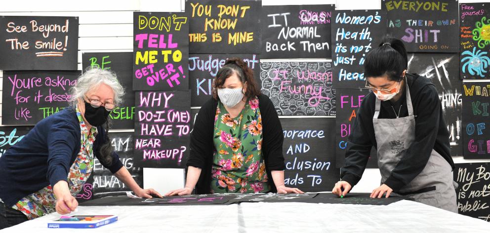 Maggie Covell (centre) works with Linda Cook (left) and Sabrina Lu of Dunedin creating art work...