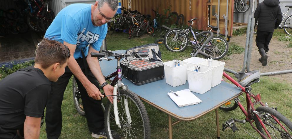 The Aranui Bike Fixup group founder Steven Muir helps a young cyclist fix a bike. Photo: John...