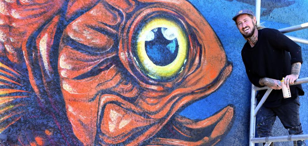 Street artist Cinzah Merkens, of Napier, works on a mural in Dunedin’s Buller St designed to draw...