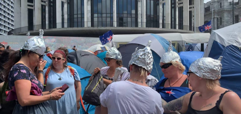 People are seen wearing hats made of tinfoil at the Parliament protest after the rise of a theory...