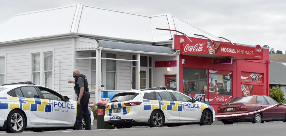 Police cars are parked outside the Mosgiel Mini Mart yesterday as inquiries continue over a...