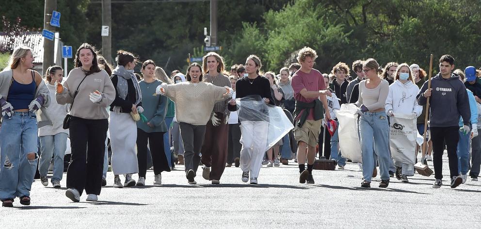 Students carrying bags and brooms arrive in Castle St yesterday during the annual North Dunedin...