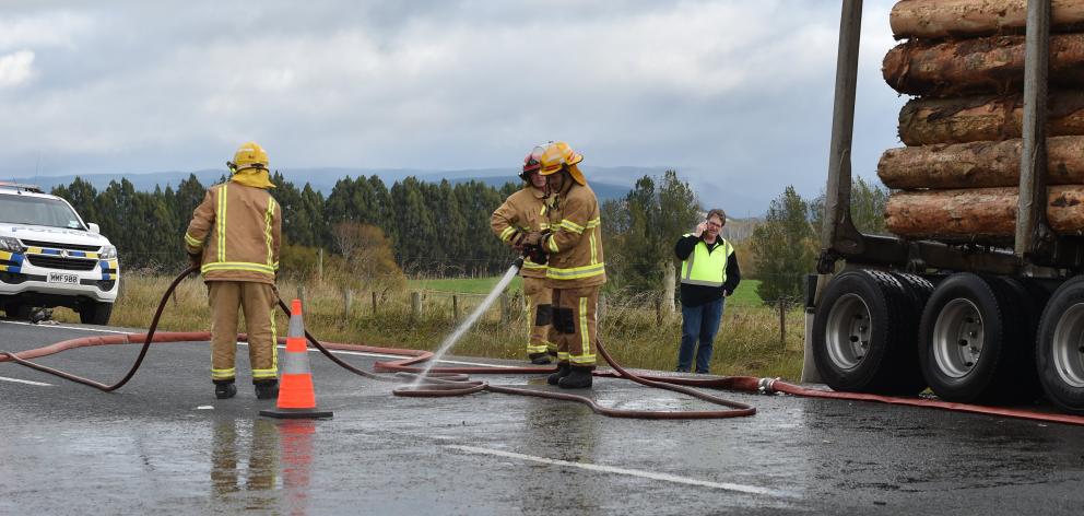 Firefighters clean up State Highway1, south of Allanton, after a logging truck caught fire on the...
