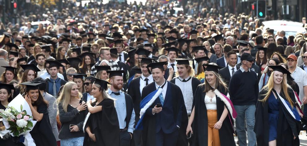 Several hundred University of Otago graduands stream along George St, Dunedin, in the university...