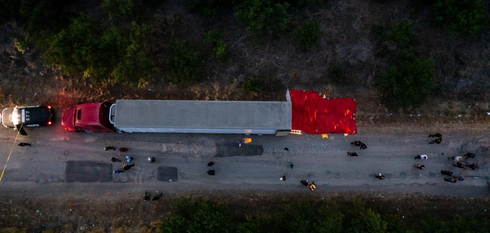 In this aerial view, members of law enforcement investigate the truck and trailer carrying the...