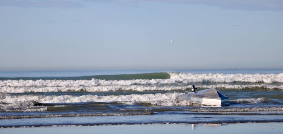 The overturned craft in the surf on Kairaki Beach this afternoon. Photo: George Heard/ NZ Herald 
