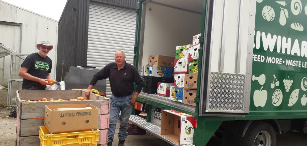 John Preedy (right) helps KiwiHarvest driver Allan Croad load fresh fruit for distribution to...