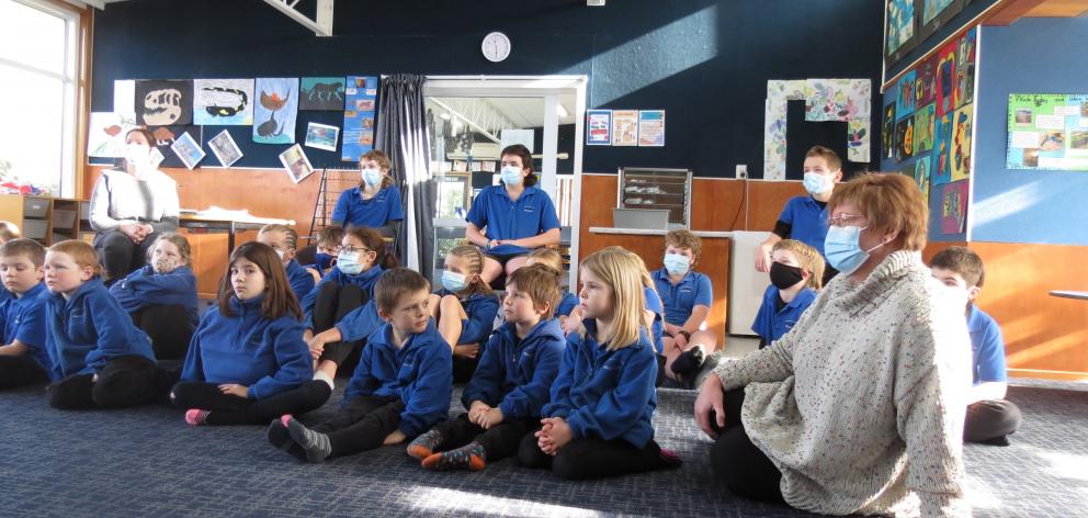 Millers Flat School principal Hilary Spedding sits with her pupils as they listen to local author...