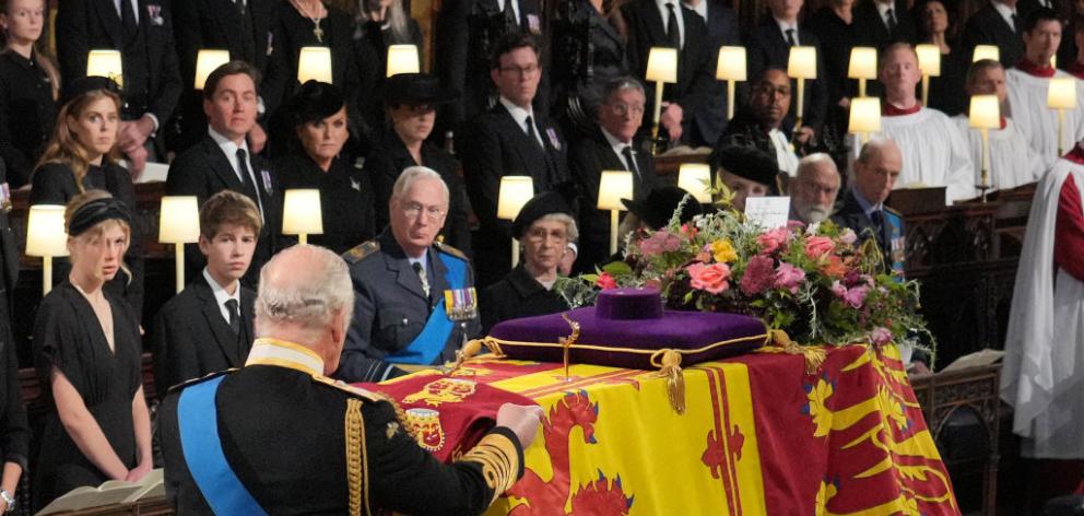 King Charles III places the the Queen's Company Camp Colour of the Grenadier Guards on the coffin...