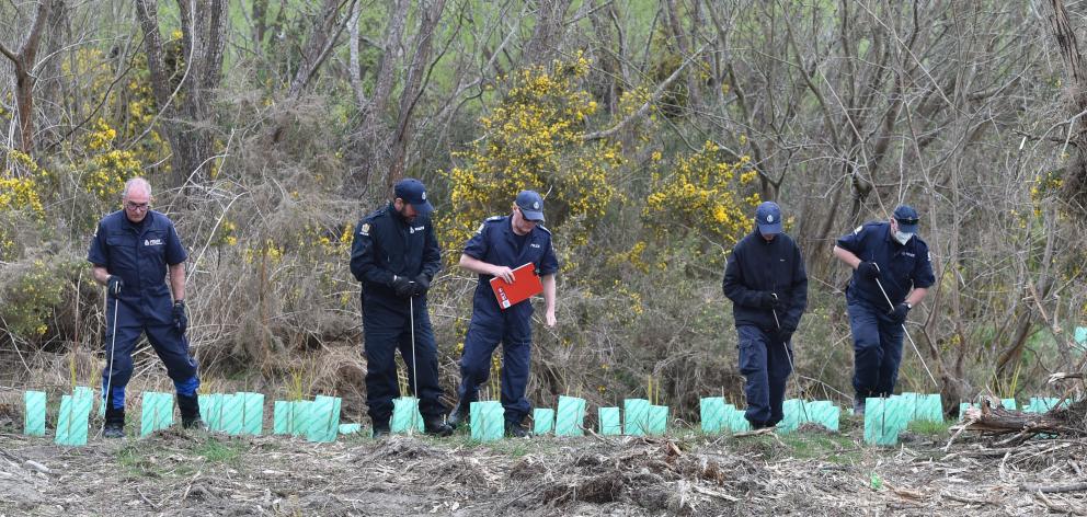 Members of a specialist police search team from Christchurch pick their way through rough ground...