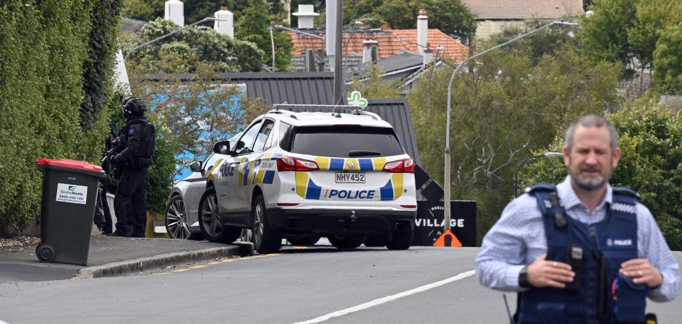 Officers from the armed offenders squad investigate a house at the intersection of Hereford St...
