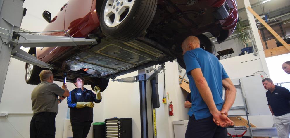 Rob Usherwood, (left), an instructor at automotive training provider Pro-Moto, talks to electric...