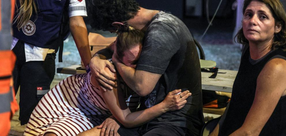 A distraught woman is comforted at the site where a rocket launched from the Gaza Strip landed in...