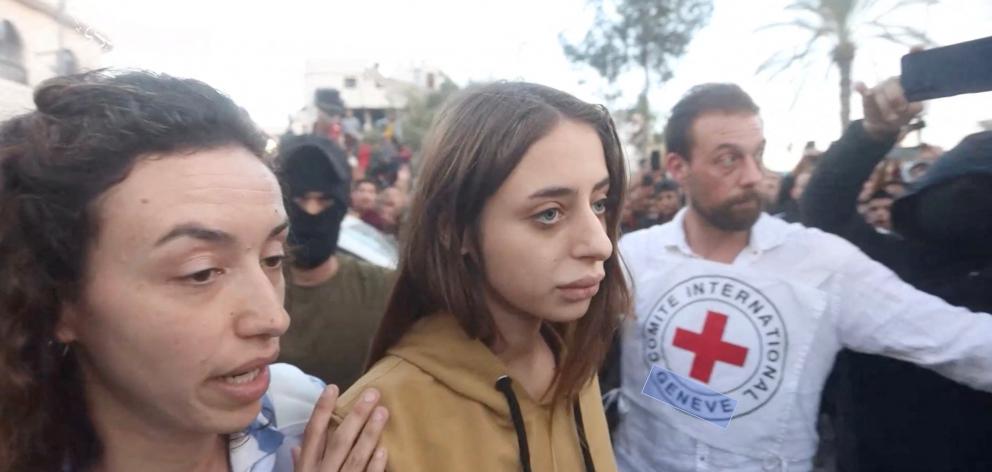 Hostages abducted by Hamas gunmen during the October 7 attack on Israel are escorted by members...