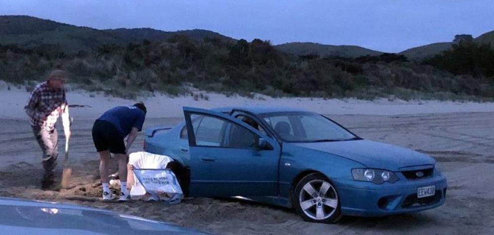 A vehicle is stuck in the sand at dusk after racing and doing doughnuts at Cannibal Bay in...