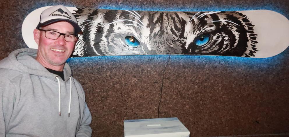 Recycled snowboard exhibition organiser Jase John with a white tiger painted on a board by...