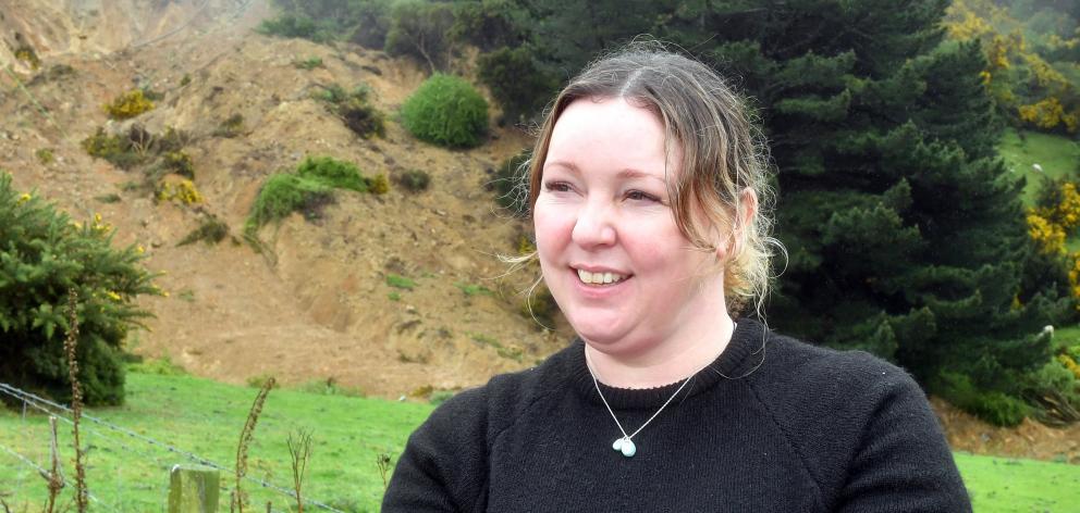 Maia resident Fiona Cadogan stands in front of the landslip that has made her home uninhabitable.