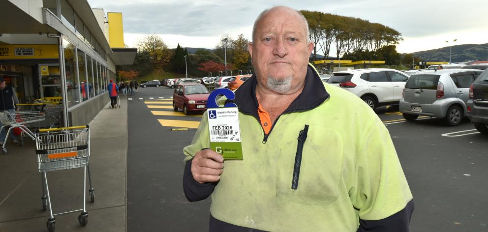 Peter Walsh holds up his mobility parking permit at Pak’nSave Dunedin, after observing people...
