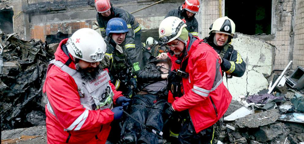 Firefighters and paramedics evacuate a disabled man from a destroyed multi-storey building after...
