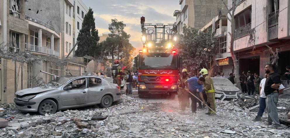 First-responders gather outside a building that was hit by an Israeli strike in Tehran on Friday,...
