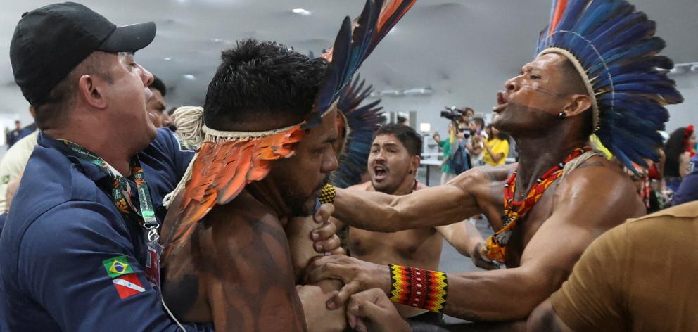 An Indigenous demonstrator is held by a staff member as protesters force their way into the...