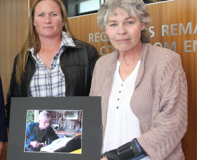 Midge Henderson (right) and her daughter Sarsha Allen hold a photograph of Ms Henderson's partner...