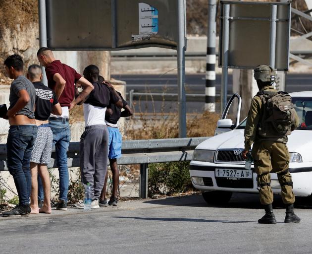 An Israeli soldier checks Palestinians at a checkpoint in Hebron in the Israeli-occupied West...