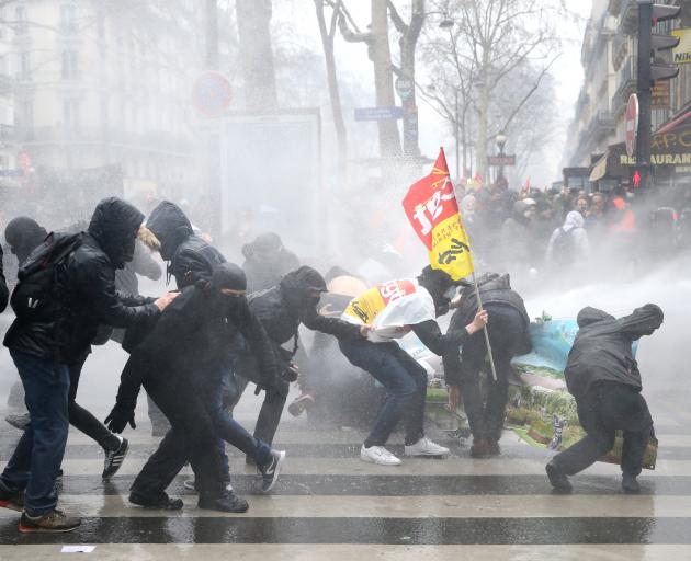 French riot police use water cannons during clashes with masked protesters attending a...