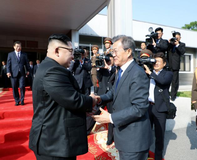 South Korean President Moon Jae-in (rught) shakes hands with North Korean leader Kim Jong Un...